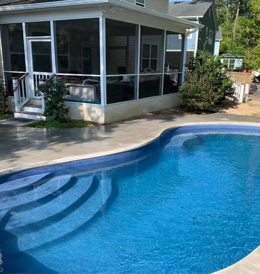 Freeform backyard swimming pool with curved entry steps and screened patio